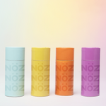 Load image into Gallery viewer, Four colored NÖZ sunscreen sticks standing side to side against a gradient background
